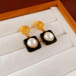 Elegant vintage black and gold heart earrings with pearl accents in a white velvet jewelry box