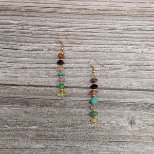 Detail of colorful stacked stone teardrop earrings with gold bead accents on wood