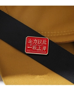 Detail of red enamel badge with gold text Go All Out pinned on a black strap
