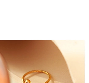 Macro detail of a minimalist gold ring set with a small diamond in warm lighting