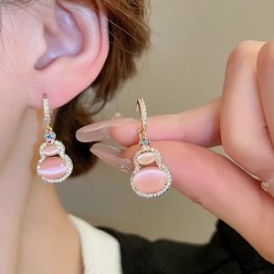 Macro detail of cat's eye gourd earrings with rose gold plating and crystal inlay