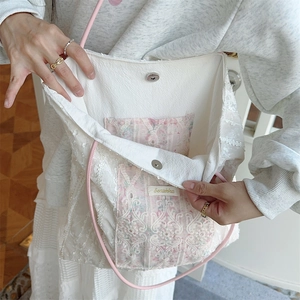 Detail of lace tote bag interior featuring pink floral pocket and magnetic metal clasp