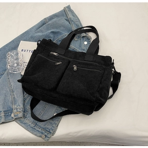 Top-down view of black corduroy multi-pocket tote bag styled with denim and magazines