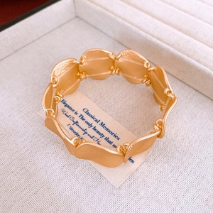 Macro detail of matte gold wave-shaped metal bracelet segments on fabric jewelry box