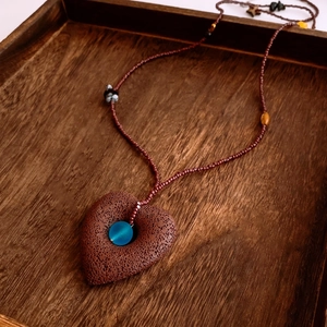 Macro detail of heart-shaped volcanic stone pendant with blue zircon on wooden tray