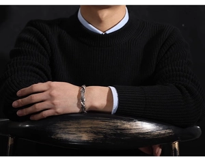 Close-up of retro silver woven texture bracelet on male wrist against dark wood background