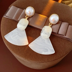 Macro shot of French vintage pearl earrings with marble resin pendants on velvet box