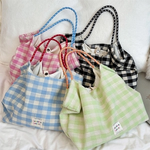Stack of canvas plaid tote bags in pink, black, blue, and green with drawstring ropes