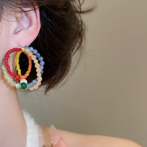 Close-up of vibrant multi-color beaded flower earrings on model for bohemian style