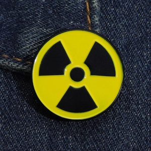 Detail of yellow and black radioactive symbol enamel pin on dark blue denim fabric