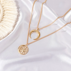 Layered gold necklace featuring crescent moon and sun pendants on elegant white silk