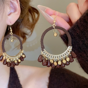 Detail of bohemian cotton-wrapped hoop earrings with golden filigree and water drop charms
