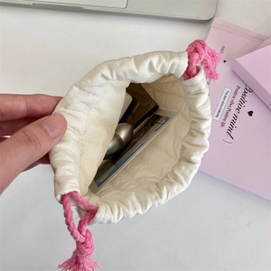 Quilted drawstring storage bag showing internal capacity for cosmetics and earbuds
