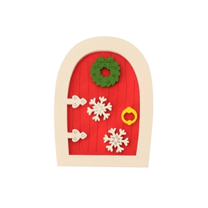 Miniature wooden Christmas elf door with red panels and green festive wreath on white background