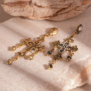 Gros plan détaillé de boucles d'oreilles croix dorées avec strass noirs et perles