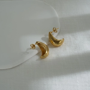 Detail of polished gold crescent stud earrings with a smooth metallic finish