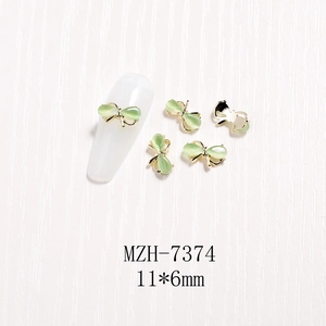 Details von 3D-Bogen-Nagelcharms mit grünem Katzenaugenstein und Goldrand in 11x6mm