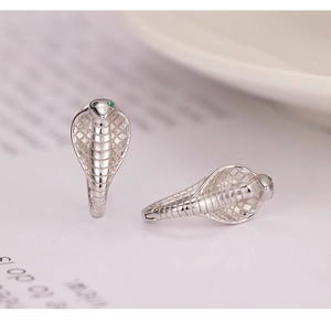 Macro shot of silver cobra hoop earrings with green gemstone eyes and detailed scales