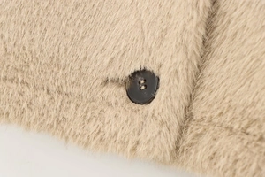 Detailed close-up of marble pattern button on camel faux fur jacket with soft plush texture