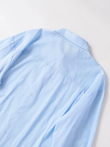 Detalle de cerca del cuello y costuras del hombro de una camisa azul claro de manga larga
