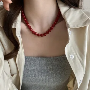 Gros plan d'un collier de perles rouges vintage avec finition brillante sur chemise