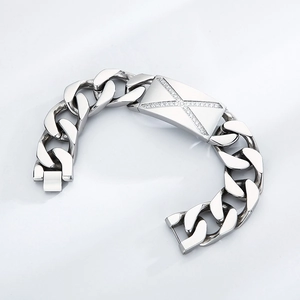 Gros plan sur un bracelet gourmette argenté avec un charm croix serti de zircons
