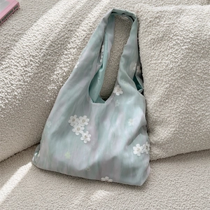 Detail view of 3D white embroidered flowers on a mint green and purple canvas tote bag