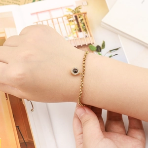 Close-up of golden circle pendant bracelet with inlaid stones on female wrist
