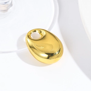 Macro shot of a polished gold teardrop pendant with a smooth reflective metallic surface