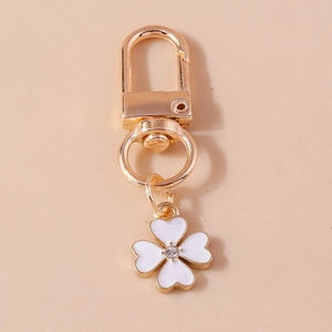 Golden keychain featuring a white clover pendant with rhinestones and elegant butterfly motifs