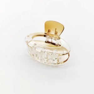 Close-up of a gradient brown acetate hair claw clip with transparent finish and gold spring