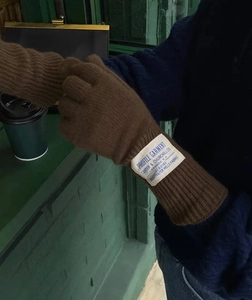 Detalle de guantes de punto de lana marrón con etiqueta textil y función de pantalla táctil