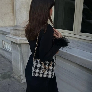 Detail shot of black and white houndstooth chain bag with gold metal hardware and flap