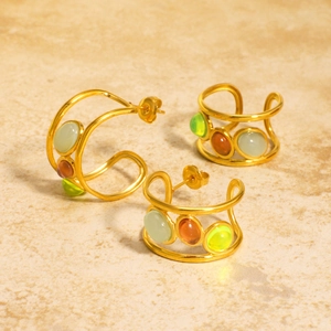 Golden C-shaped earrings and ear cuff set with multi-colored natural stones on marble