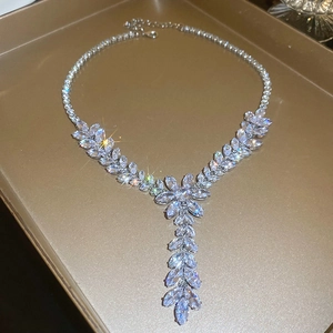 Detail of silver floral necklace with clear crystals displayed on a golden tray