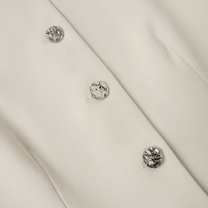 Detailed view of beige twill fabric and three silver irregular texture metal buttons