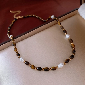 Détail du collier de perles d'eau douce et œil de tigre dans un écrin en velours brun