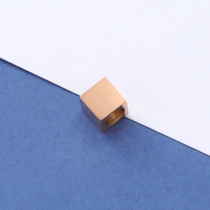 Macro view of a rose gold square spacer bead with internal threading for DIY jewelry