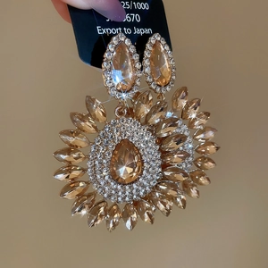 Macro detail of luxury teardrop crystal earrings with sparkling champagne floral design