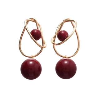 Minimalist geometric gold earrings with red spheres in a symmetrical circular design
