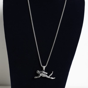 Macro detail of high-polish stainless steel diver pendant showing oxygen tank and fins