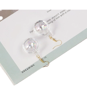 Elegant iridescent glass ball drop earrings with golden hooks on minimalist display