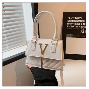 Close-up of white crossbody bag with golden V-logo, tassel detail and quilted texture