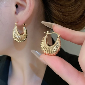 Close-up of gold croissant earrings with pleated texture and C-shaped metal design