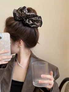 Dettaglio di un grande scrunchie leopardato sui capelli con texture effetto seta