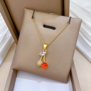 Titanium steel gold cherry necklace with crystals in a gift box on white silk background
