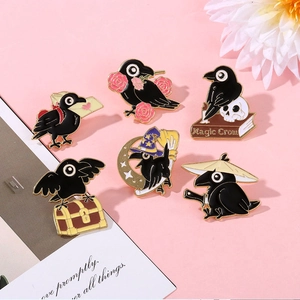Detailed set of six magic crow enamel pins with black and gold finish on pink surface