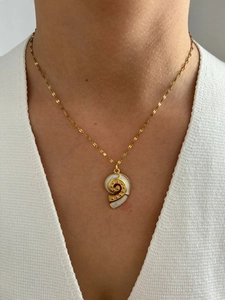 Detailed close-up of a 18K gold-plated spiral seashell pendant worn on a dainty gold chain