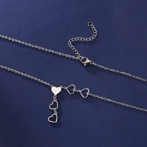 Elegant stainless steel necklace with polished heart pendants on blue background