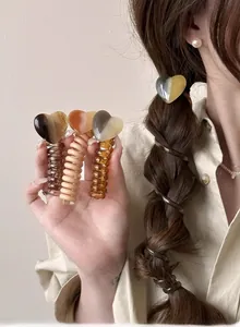 Macro shot of heart-shaped charm spiral hair ties in coffee and amber colors